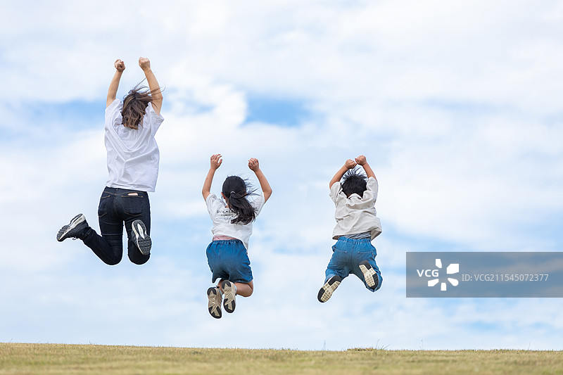 父母和孩子在阳光明媚的山丘上跳跃图片素材