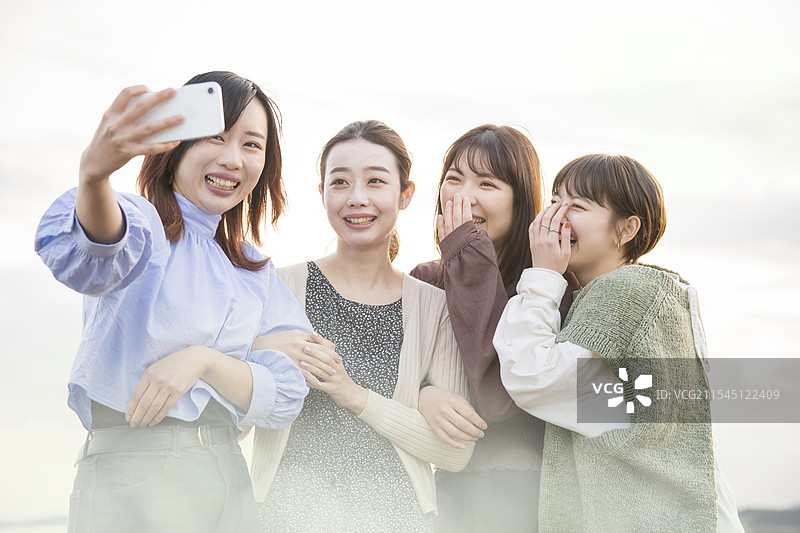 四位女性用智能手机拍照图片素材