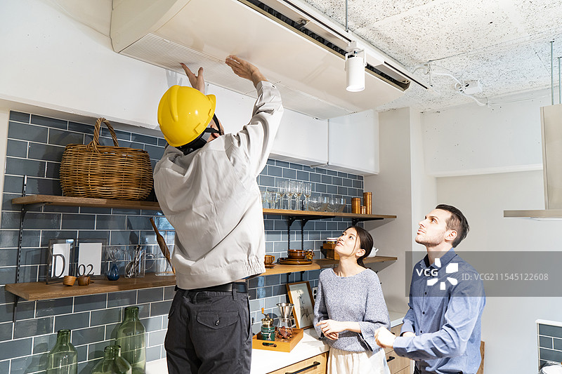 穿着黄色安全帽的维修工正在检查空调图片素材