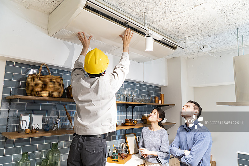 穿着黄色安全帽的维修工正在检查空调图片素材