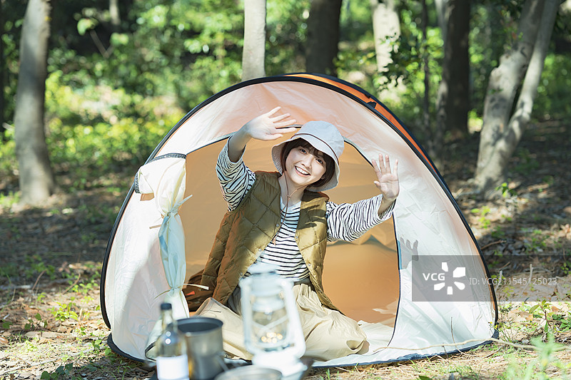 年轻女性在帐篷内微笑并挥手的独自露营照片图片素材