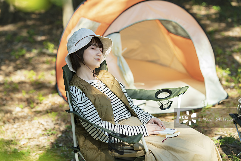 独自露营的画面：年轻女性在帐篷前小憩图片素材