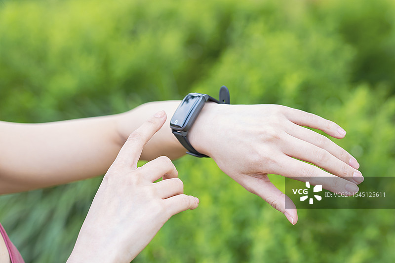 穿着运动服的女性正在操作智能手表图片素材