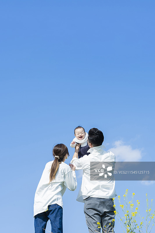 父母在蓝天之下高高举起他们的宝宝图片素材