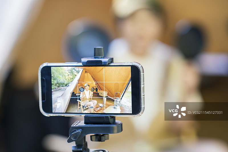 年轻女性露营者在帐篷里用智能手机拍照图片素材