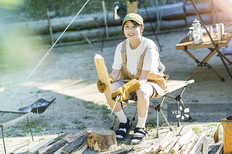 独自露营的画面 - 年轻女性在劈木头图片素材