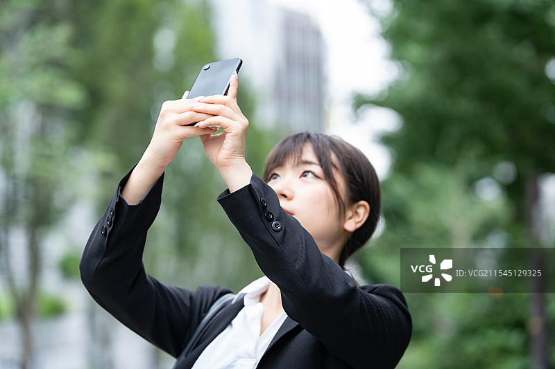 穿着西装的年轻女性用智能手机拍照图片素材