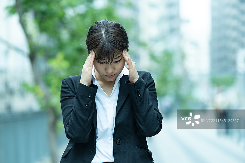 穿着西装的年轻女性正在忍受头痛图片素材