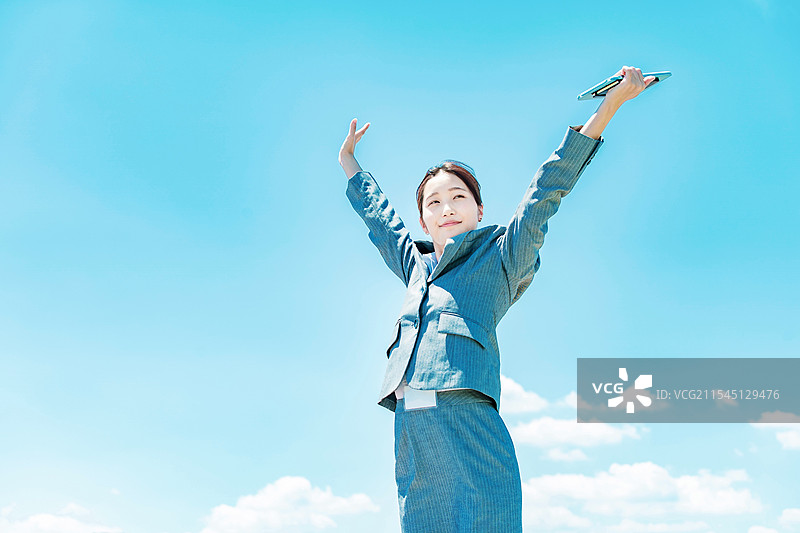年轻女商人在蓝天背景下站立图片素材