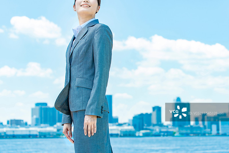 年轻女商人在城市中心与蓝天背景下站立图片素材