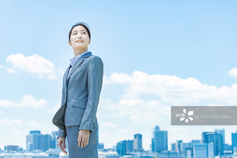 年轻女商人在城市中心与蓝天背景下站立图片素材