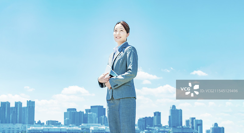 年轻女商人在城市中心与蓝天背景下站立图片素材