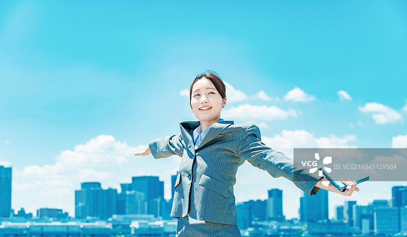 年轻女商人在城市中心与蓝天背景下站立图片素材