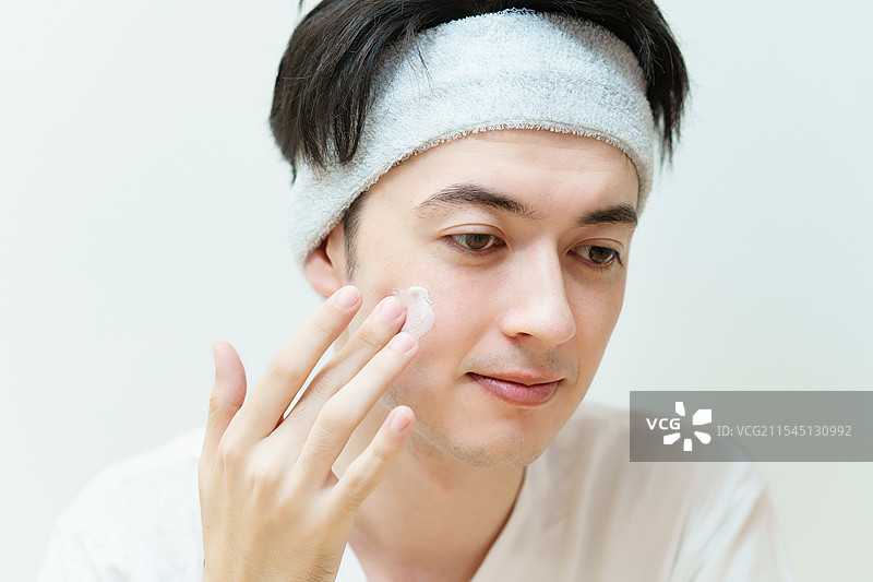 年轻男子在脸上涂抹面霜图片素材