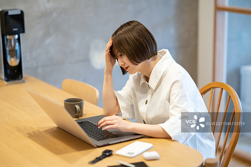 女人捧着头，凝视着笔记本电脑图片素材