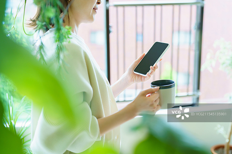 房间里拿着智能手机的女人图片素材