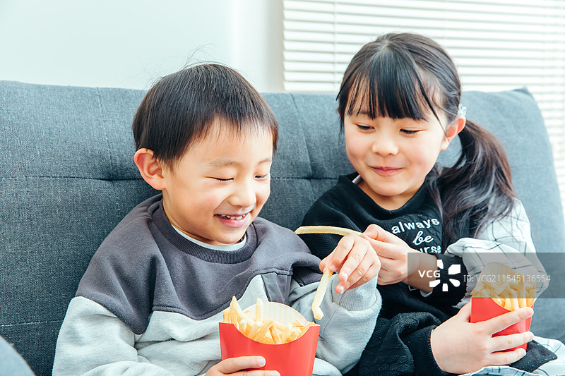 孩子们坐在沙发上吃零食图片素材
