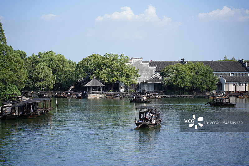 乌镇江南水乡白墙黑瓦绿树里的渔船蓝天倒影图片素材