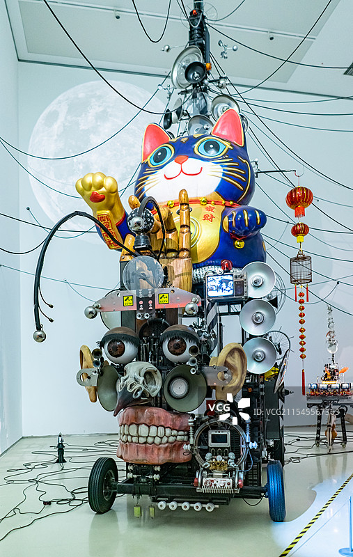 中国山东济南美术馆博物馆双年展，用废品垃圾材料制作组装焊接的招财猫机械装置艺术，室内人图像摄影图片素材