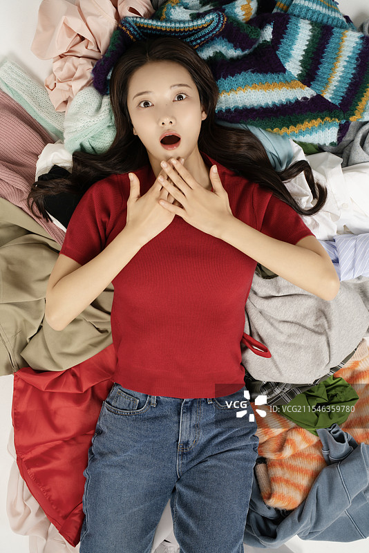 一位20多岁的女性躺在一堆衣服上图片素材