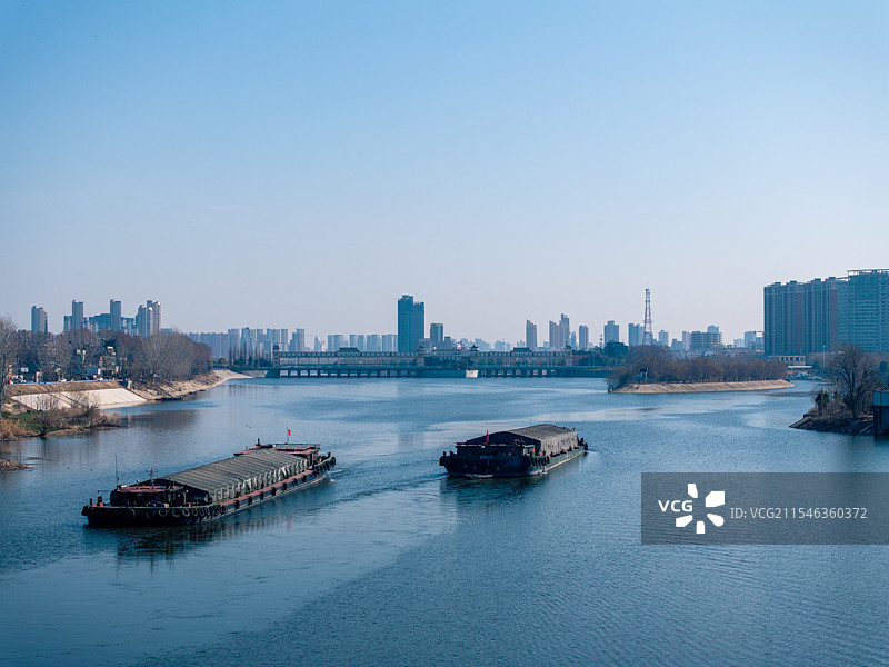 低视角周口沙河货船航行中与城市天际线图片素材