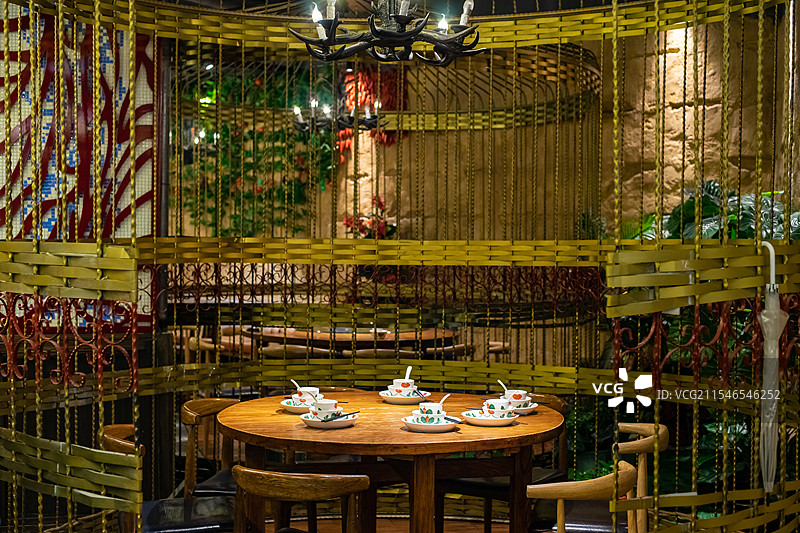 中国餐饮餐厅饭店饭馆行业，空的餐桌拍摄主题，巨大的铁质鸟笼里木制圆桌上的餐具，室内无人图像摄影图片素材
