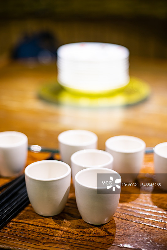 中国餐饮餐厅饭店饭馆行业，空的餐桌拍摄主题，中国传统木制圆桌上的叠起来的茶碗餐具，室内无人图像摄影图片素材