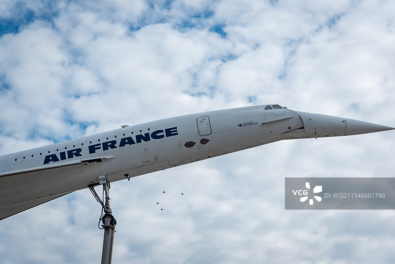 法国航空飞机停在停机坪上，机身洁白，印有蓝色Air France字样，机头尖锐，背景是多云的天空图片素材
