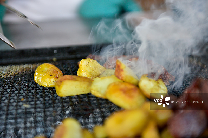 烤架上滋滋冒气的金黄土豆图片素材