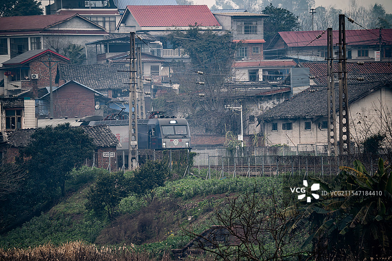 四川自贡的火车行驶于雾气笼罩的乡村房屋间图片素材