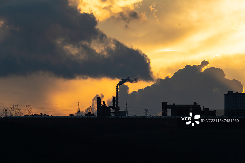 黄昏下烟囱冒烟的工厂剪影图片素材