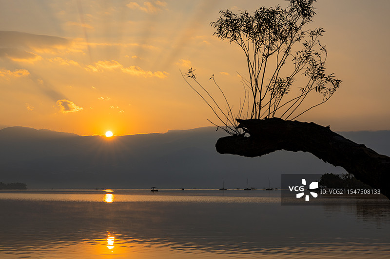 四川西昌邛海日出橘色天空丁达尔光下的湖景图片素材