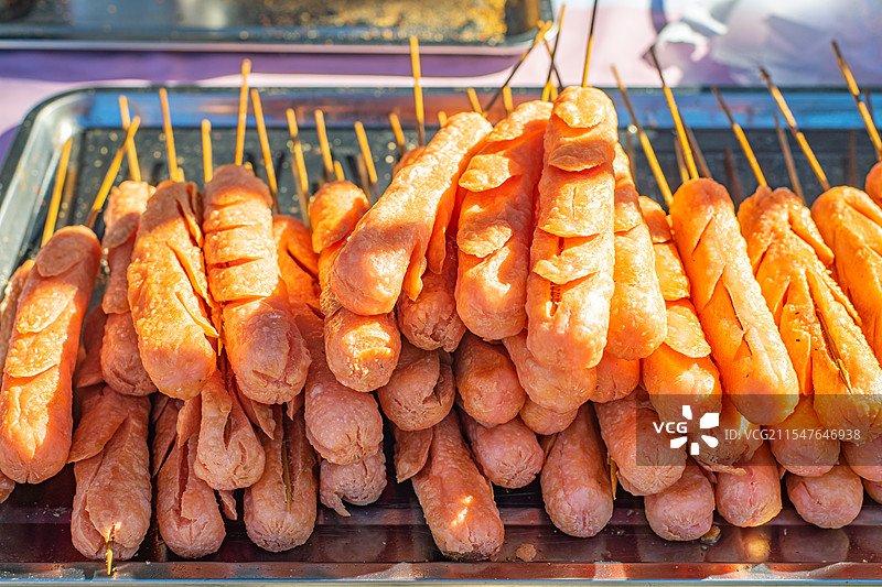 中国饮食产业拍摄主题，庙会货摊零售展示,炉子油炸的淀粉肠和一排摆设的火腿肠，白昼户外无人图像摄影图片素材