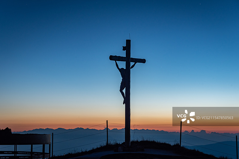 多诺米蒂日出时分，十字架与耶稣的剪影映在天空，背景呈现迷人的渐变色彩图片素材