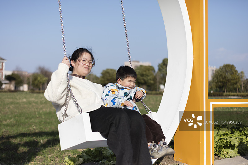 母亲和儿子在田间荡秋千图片素材