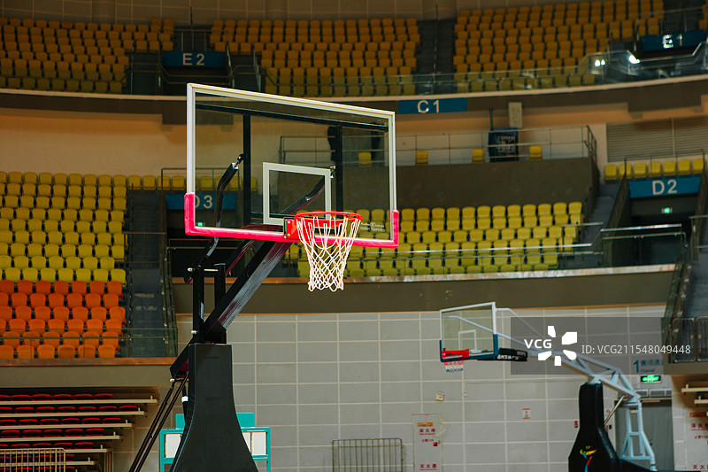 室内篮球馆的篮球框，安装在透明篮板上，篮网自然垂下。经典的体育象征，代表竞技、训练与团队合作。图片素材