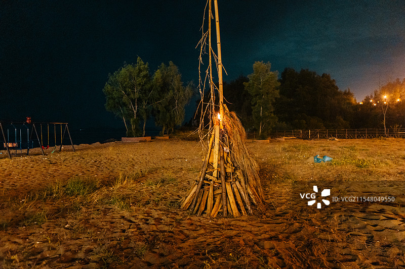夜晚篝火熊熊燃烧，火焰跳跃，温暖的余烬映照黑暗，为户外营造出温馨而富有氛围的体验。图片素材