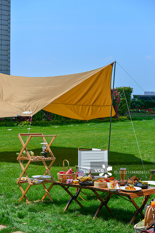 户外公园草坪露营，草坪蓝天帐篷和满桌美食图片素材