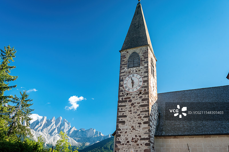多诺米蒂宁静的建筑与美丽的自然，展现出一种和谐的美感。钟楼上的大钟在蓝天和云朵的映衬，远处的山脉图片素材