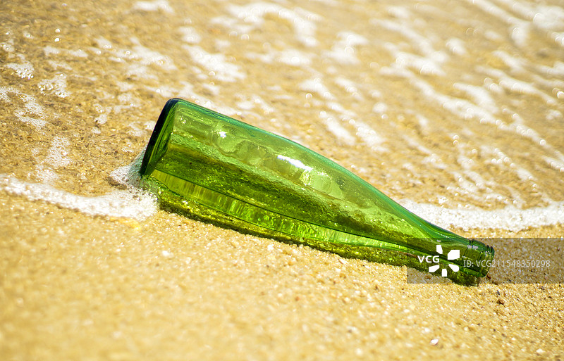 海滩潮水冲刷的绿色玻璃酒瓶图片素材