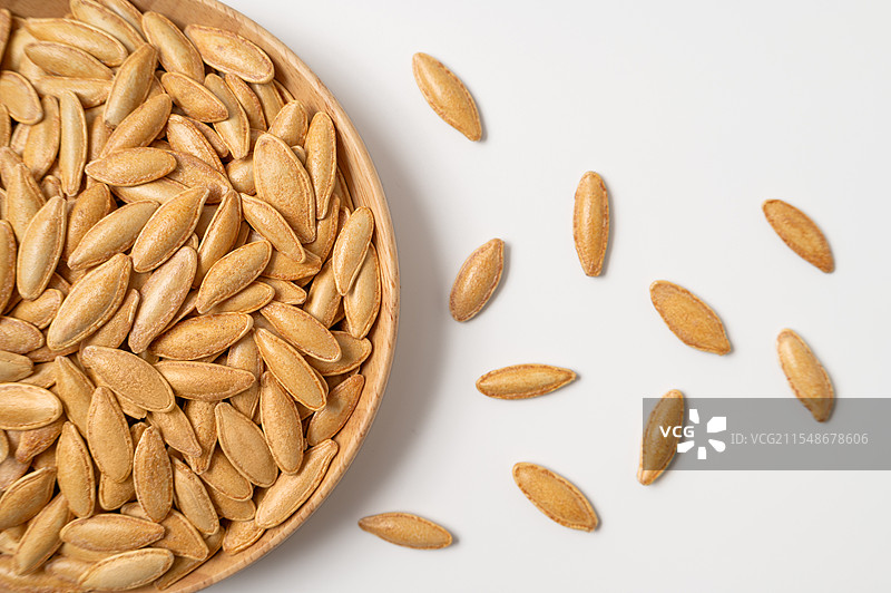 俯拍白色背景上的一盘金黄色的美人甲南瓜子图片素材