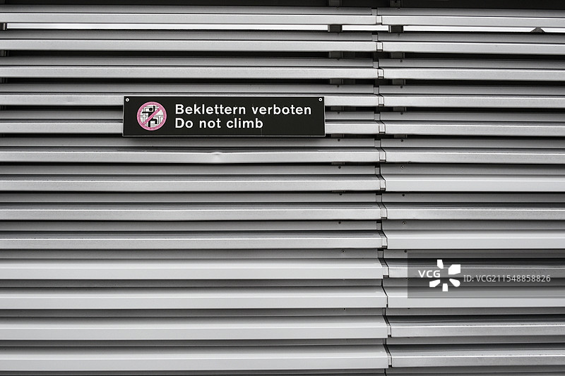 禁止攀爬的警告标志贴在波纹金属墙上图片素材