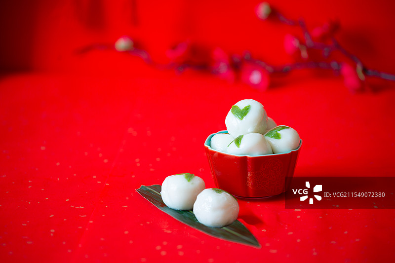 红色国风瓷碗里的汤勺内的龙舟茶汤圆元宵在红色背景中图片素材