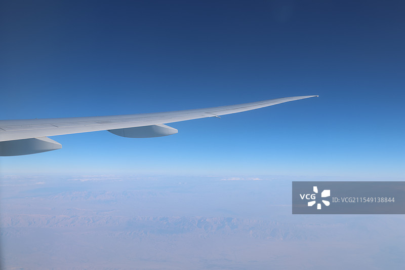 飞机机翼在蓝天下飞行的裁剪图像图片素材