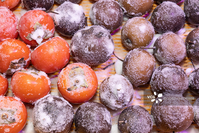 冬天中国雪乡水果摊位销售的冻梨、冻柿子等冰冻水果图片素材