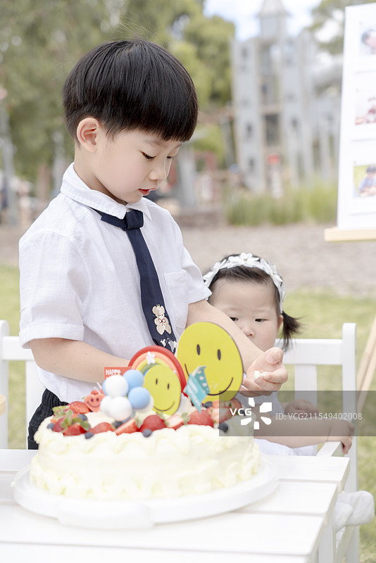 仿古城堡乐园草坪上五岁小男孩与妹妹分享生日快乐图片素材