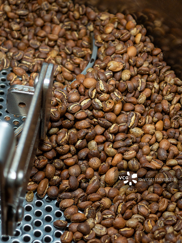 金属烘焙机中新鲜烘焙的芳香咖啡豆图片素材