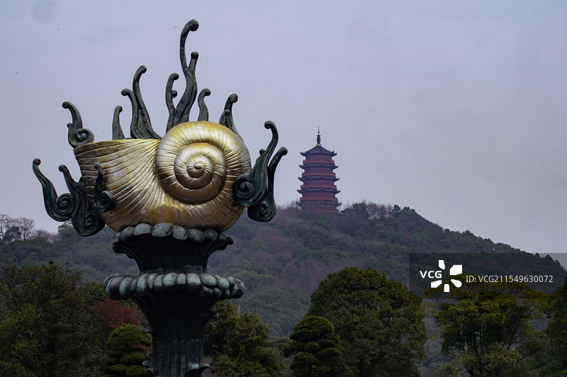 庐陵文化生园主体为金色螺旋贝壳的雕塑矗立在前，远处山峦之上，红褐相间的文星塔在云雾中若隐若现。图片素材