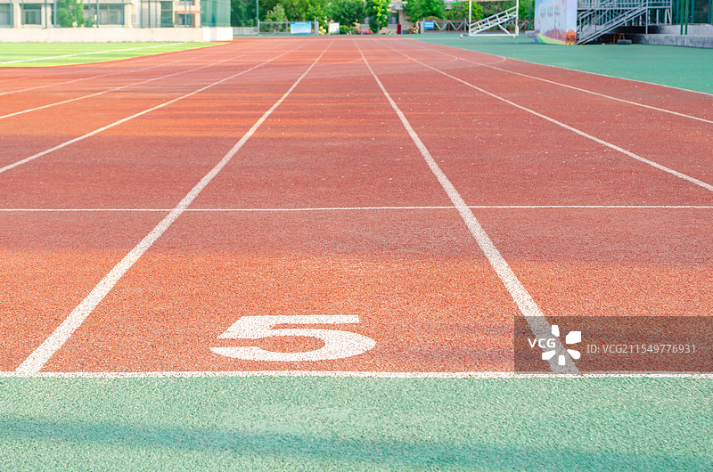 中国学校操场拍摄主题，红色塑胶跑道，绿色的操场，远处的高楼大厦，户外白昼无人图像摄影图片素材