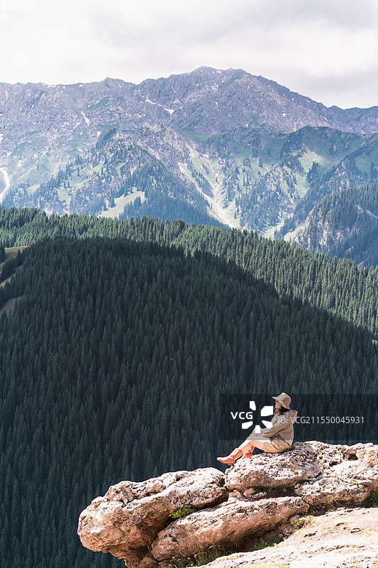 一个女人坐在新疆赛里木湖果子沟大桥山巅图片素材